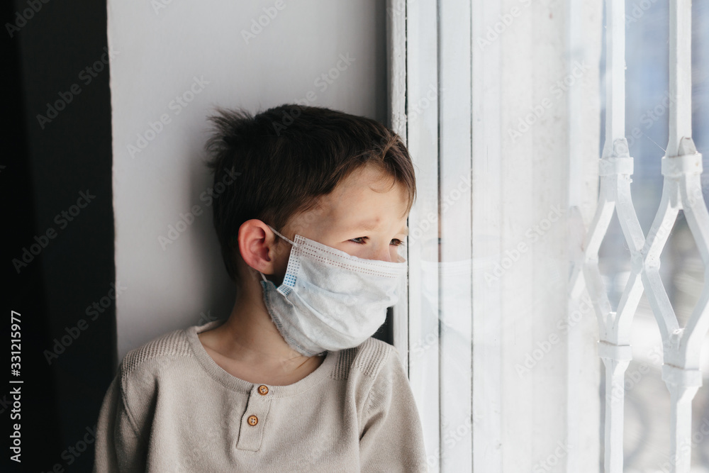 5 years boy wearing surgical protection face mask sitting at home during corona virus,covid-19 outbreak. European child concept for sickness or allergy. Quarantine time 5 years boy wearing surgical protection face mask sitting at home during corona virus,covid-19 outbreak. European child concept for sickness or allergy. Quarantine time