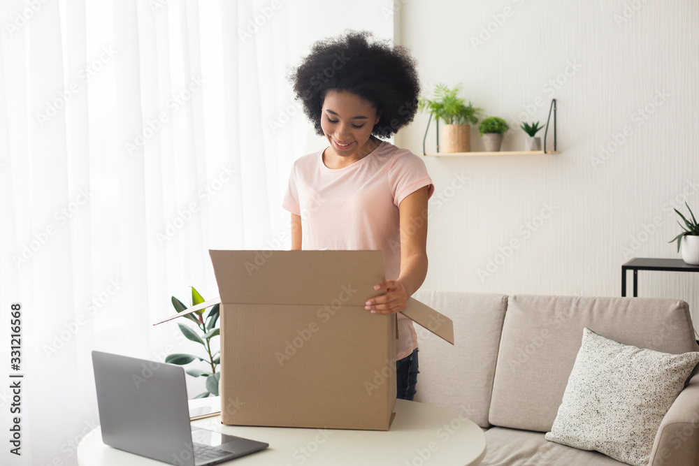 Smiling african american woman, near box and laptop Smiling african american woman, near box and laptop