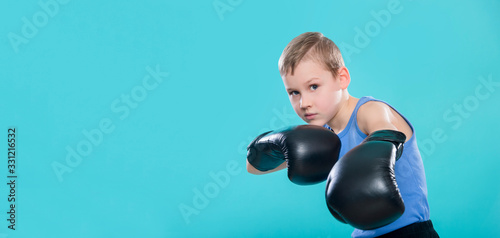 Portrait of cheerful boy with black boxing gloves on blue background © Augustas Cetkauskas