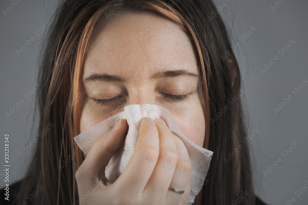 Sneezing, coughing or blowing nose in a single use paper towl. Concept of catching cold, virus or infection and not spreading it Sneezing, coughing or blowing nose in a single use paper towl. Concept of catching cold, virus or infection and not spreading it