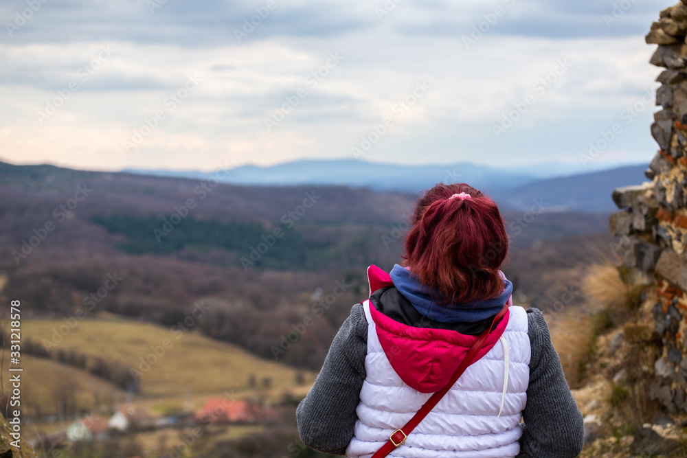 Young hiking woman staring into the distance in the autumn landscape and admiring the magnificent view.