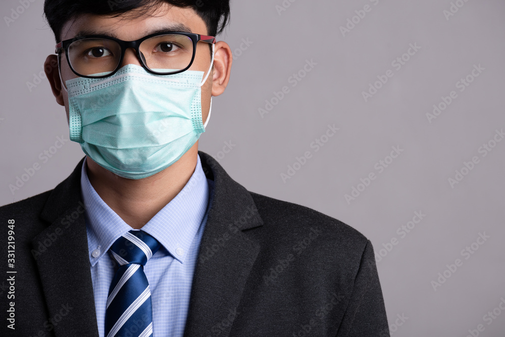 Close up of a businessman in a suit wearing Protective face mask, get ready for Coronavirus and pm 2.5 fighting against gray background. Healthcare concept. Close up of a businessman in a suit wearing Protective face mask, get ready for Coronavirus and pm 2.5 fighting against gray background. Healthcare concept.