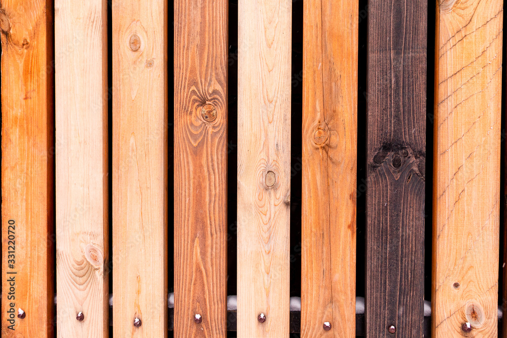 Rustic wooden fence made from treated differently colored boards. Vertical background wall made of vintage pine wood in vintage style. Rustic wooden fence made from treated differently colored boards. Vertical background wall made of vintage pine wood in vintage style.