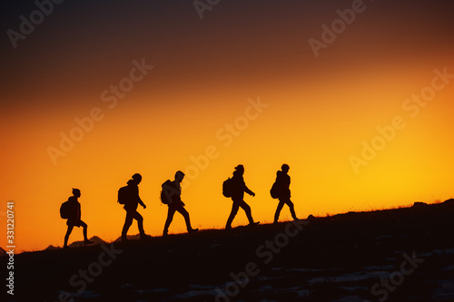 Five hikers going uphill at sunset