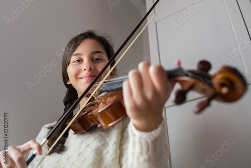 Young smiling girl student practice violin at home