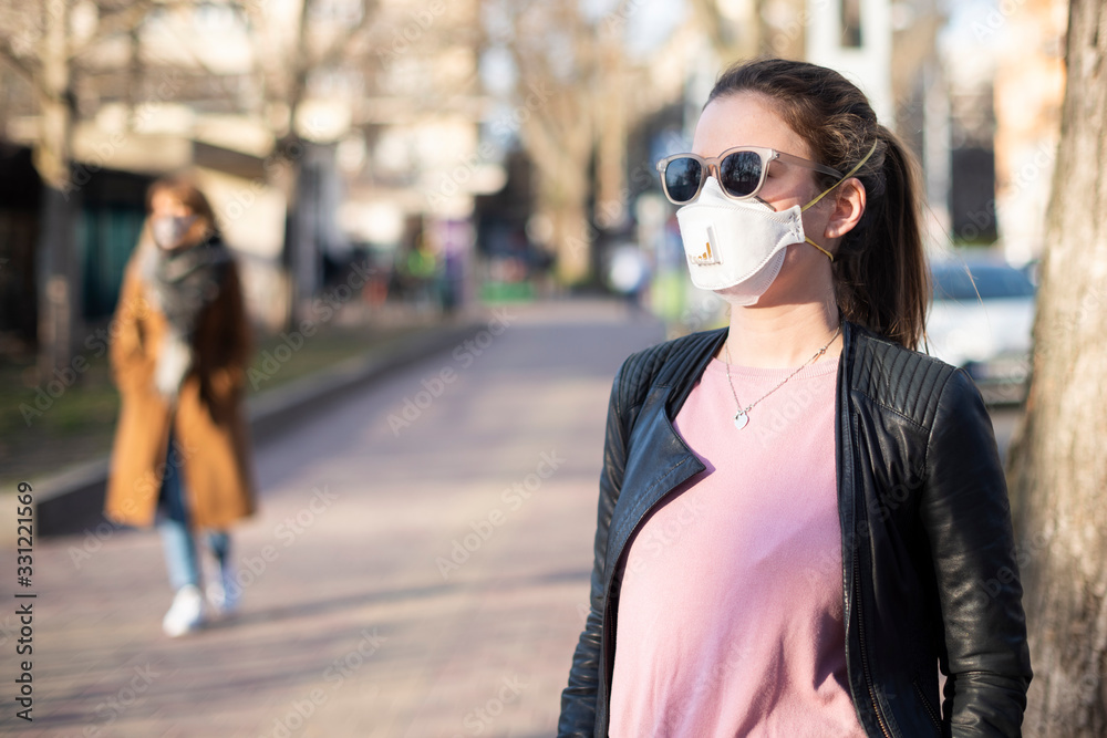 Portrait of young woman wearing a face mask in the street during infection