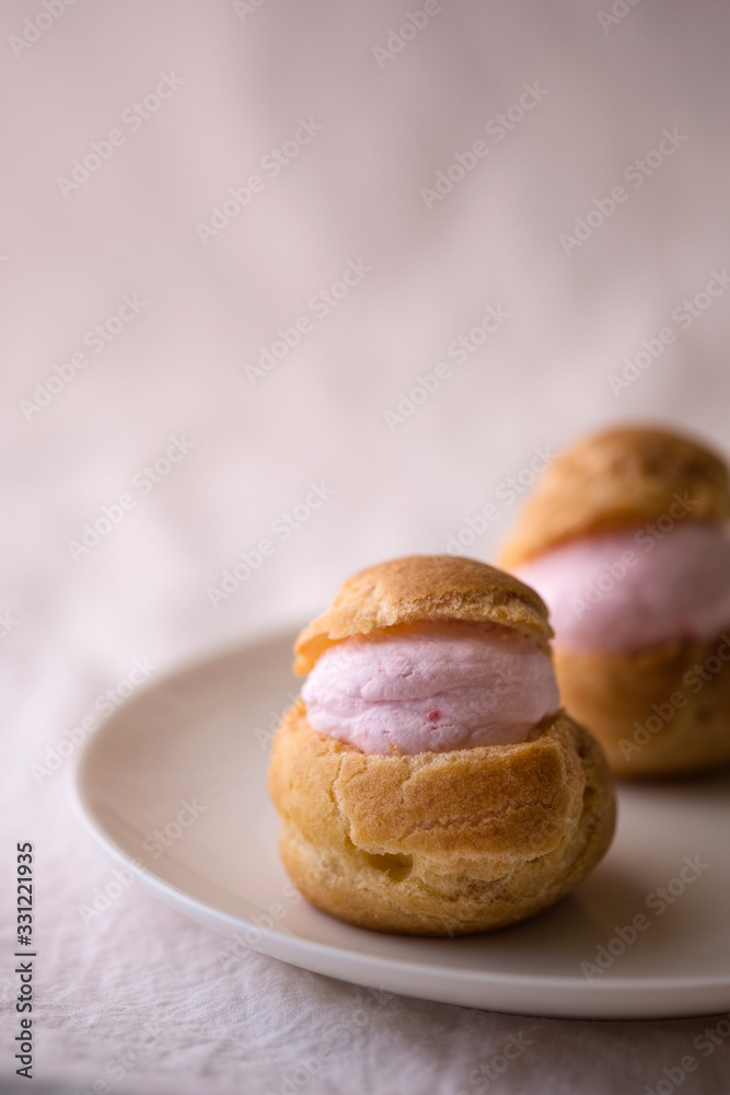 Homemade choux cream or cream puffs with strawberry cream on pink background. Homemade choux cream or cream puffs with strawberry cream on pink background.