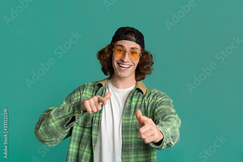 Papier peint Portrait of cool young guy in sunglasses pointing at you on color background
