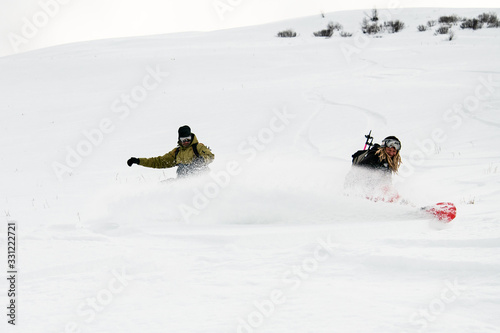 Two freeride snowboarders roundly descends from the mountain in freeride style photo