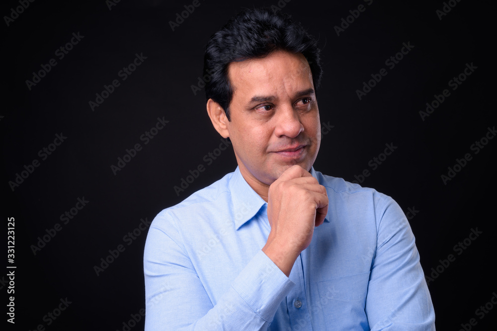 Mature handsome Indian businessman against black background