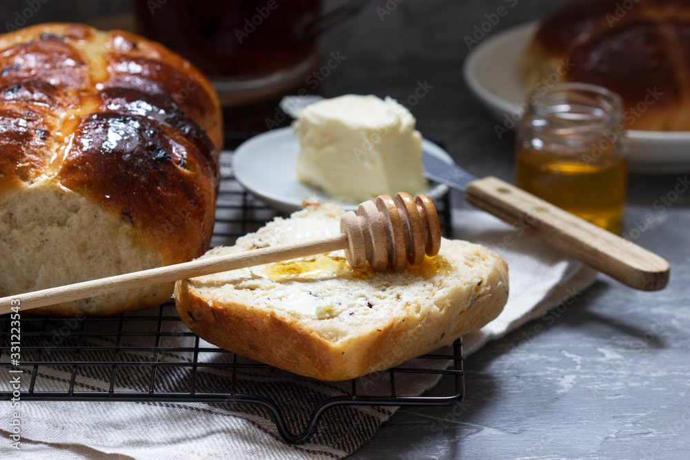Traditional hot cross buns with honey and butter on a concrete background.