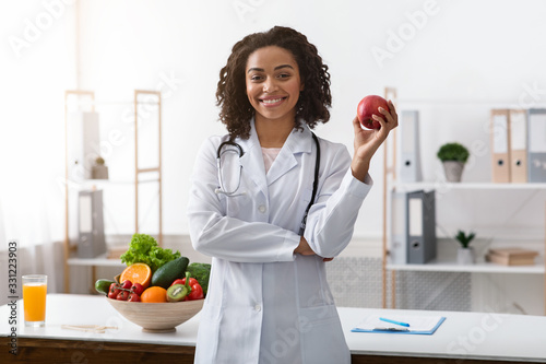 Pretty black lady dietologist holding apple in her hand