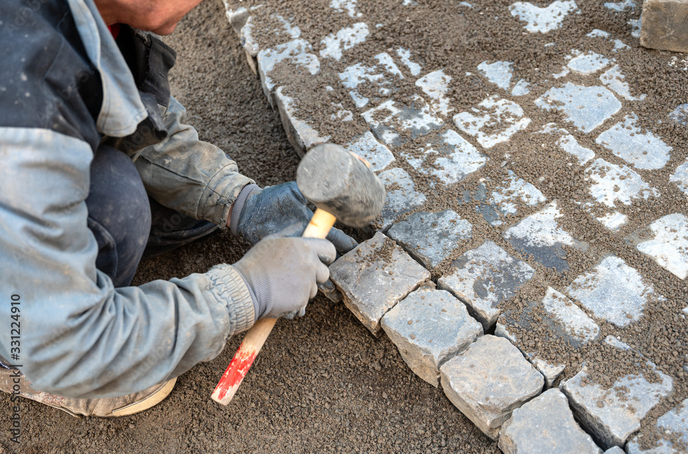Worker making the pavement of stone blocks Worker making the pavement of stone blocks