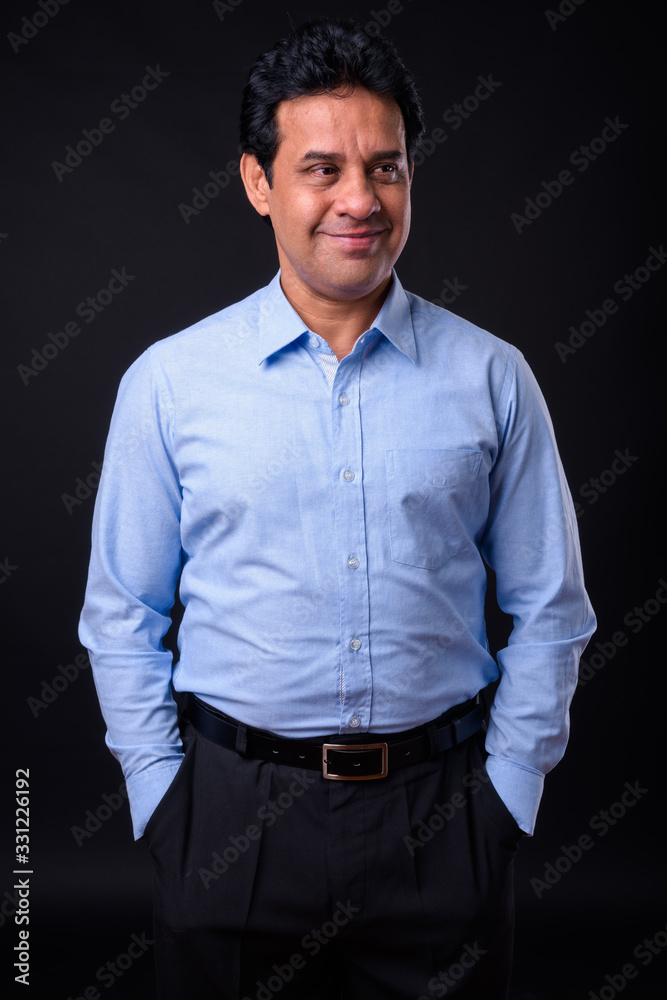 Obraz premium Mature handsome Indian businessman against black background