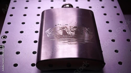 Engraving of a metal flask drawing of a ship by a laser engraver