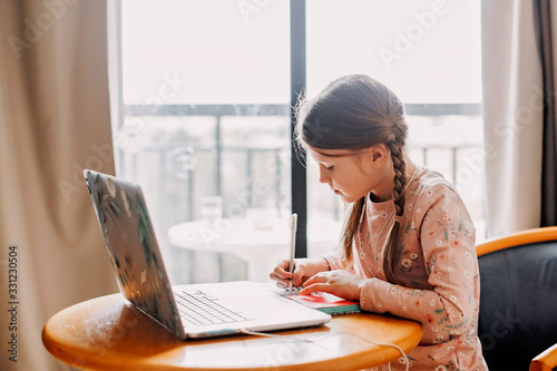 schoolgirl does homework laptop at home,quarantine
