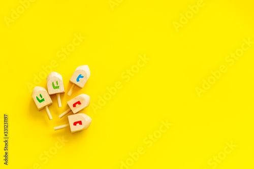 Hanukkah dreidels on yellow table. Jewish holideys concept. Top view. space for text