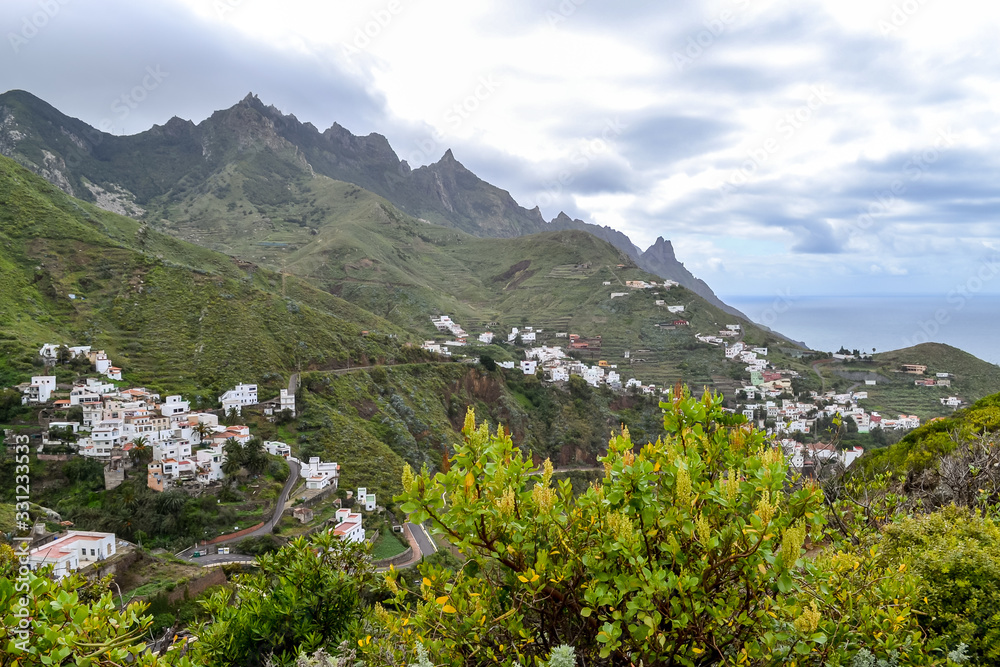 View of the town of Taganana in the north of Tenerife. Mountain green landscape with many small white houses on the ocean coast.