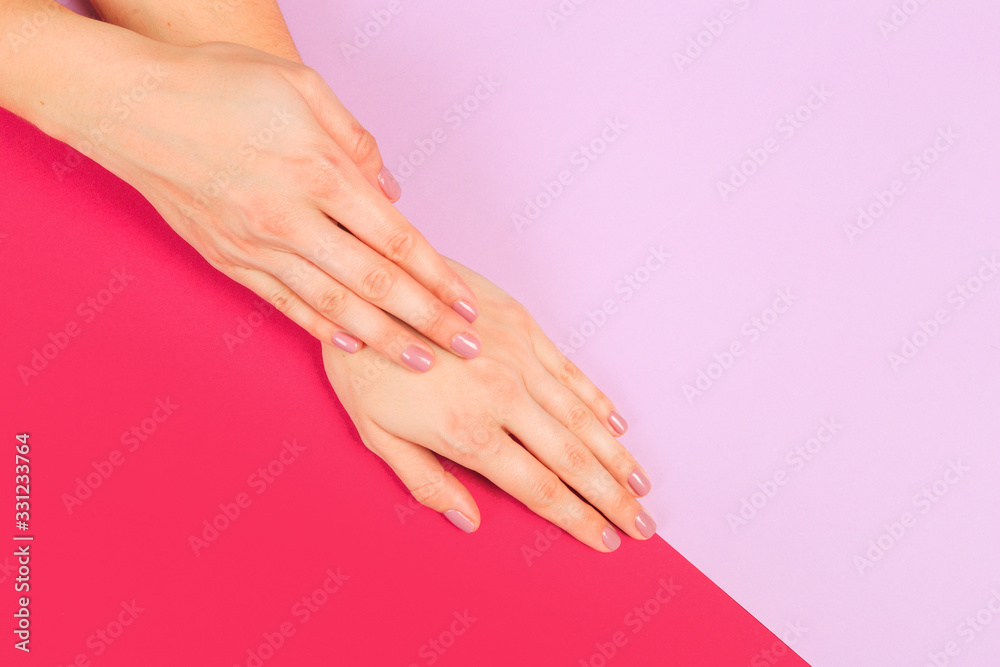 Fototapeta female manicure. Beautiful young woman's hands on color pink background - Image