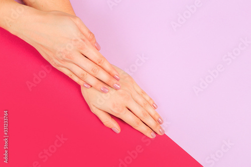 Fototapeta Naklejka Na Ścianę i Meble -  female  manicure. Beautiful young woman's hands on color pink  background - Image