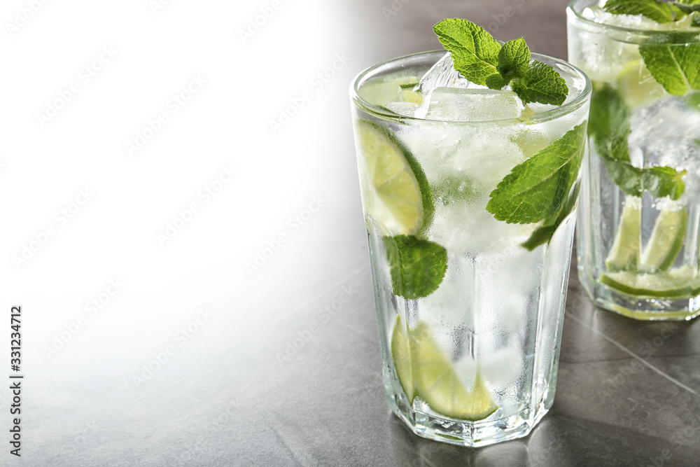 Tasty Mojito cocktail with ice cubes on light grey table, closeup. Space for text Tasty Mojito cocktail with ice cubes on light grey table, closeup. Space for text