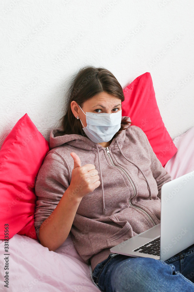 Young woman working at home during quarantine. Sick woman wearing face mask with laptop at home. Young woman working at home during quarantine. Sick woman wearing face mask with laptop at home.