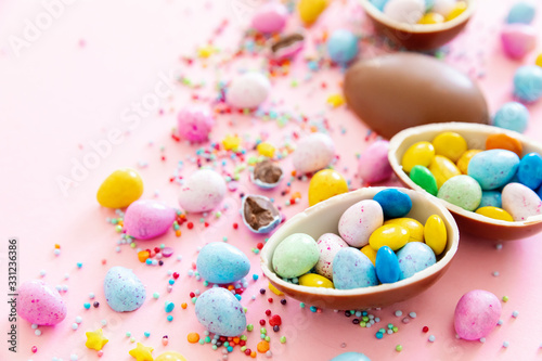 Chocolate Easter eggs with multi-colored candy decorations. Copy space © smishura