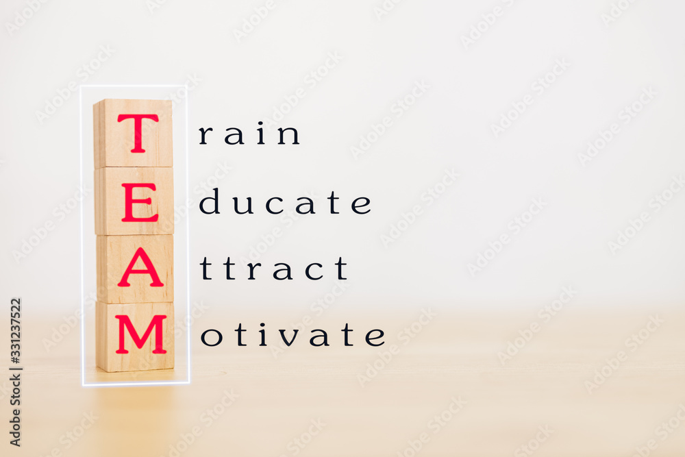 Fototapeta premium Motivation teamwork and team building concept. Wooden block stack up and word TEAM, Train, Educate, Attract, Motivate on wooden table. With copy space for your text.