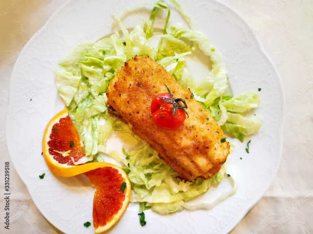 Delicious fresh fried fish with lettuce on white plate Delicious fresh fried fish with lettuce on white plate
