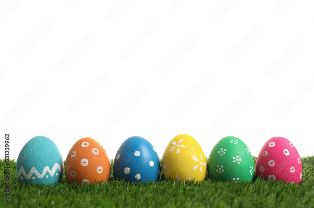 Colorful Easter eggs in green grass on white background