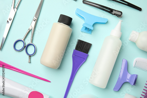 Professional tools for hair dyeing on light blue background, flat lay