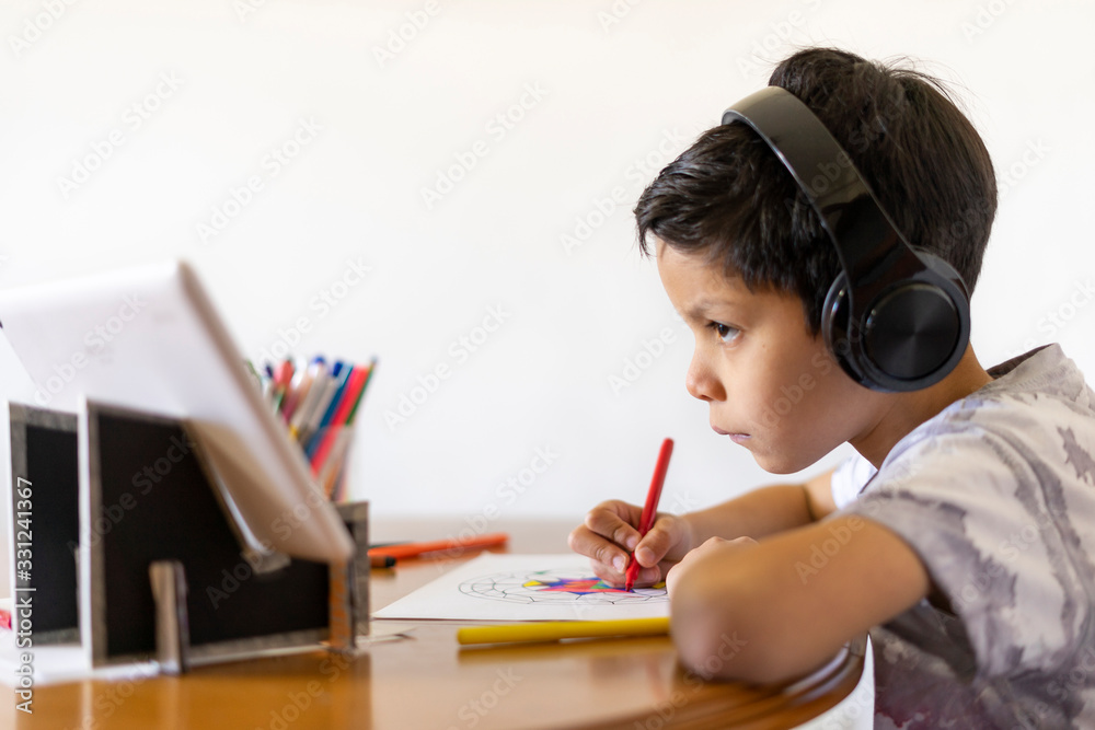 Shot of an adorable boy painting a mandala with his colored markers listening to music with headphones at home Shot of an adorable boy painting a mandala with his colored markers listening to music with headphones at home