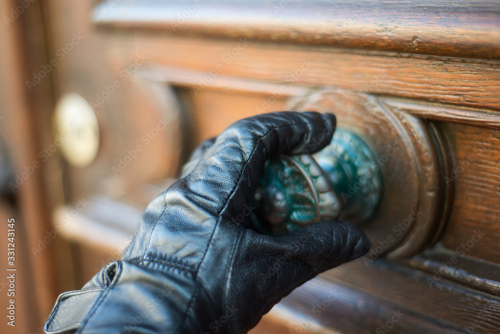 Closeup of hand of man touching a door handle with glove to protect against the coronavirus in the street Closeup of hand of man touching a door handle with glove to protect against the coronavirus in the street