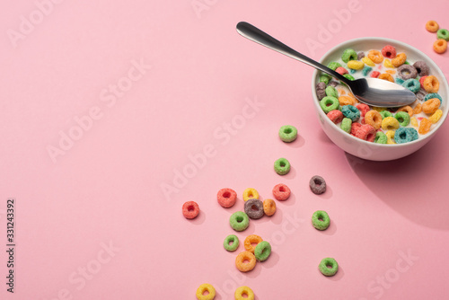 bright colorful breakfast cereal with milk in bowl with spoon on pink background © LIGHTFIELD STUDIOS