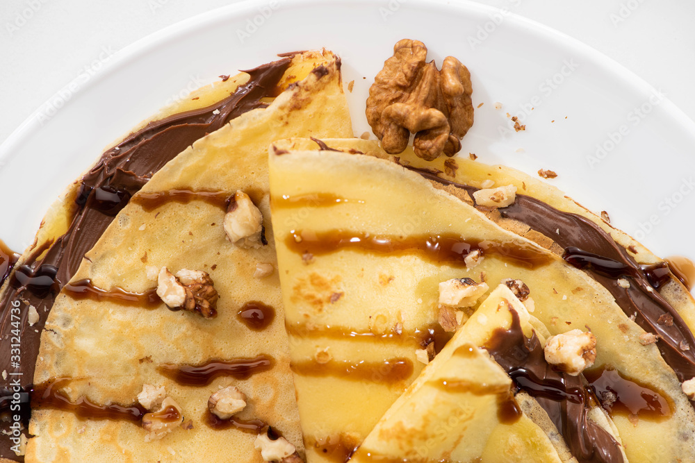 top view of tasty crepes with chocolate spread and walnuts on plate on white background top view of tasty crepes with chocolate spread and walnuts on plate on white background
