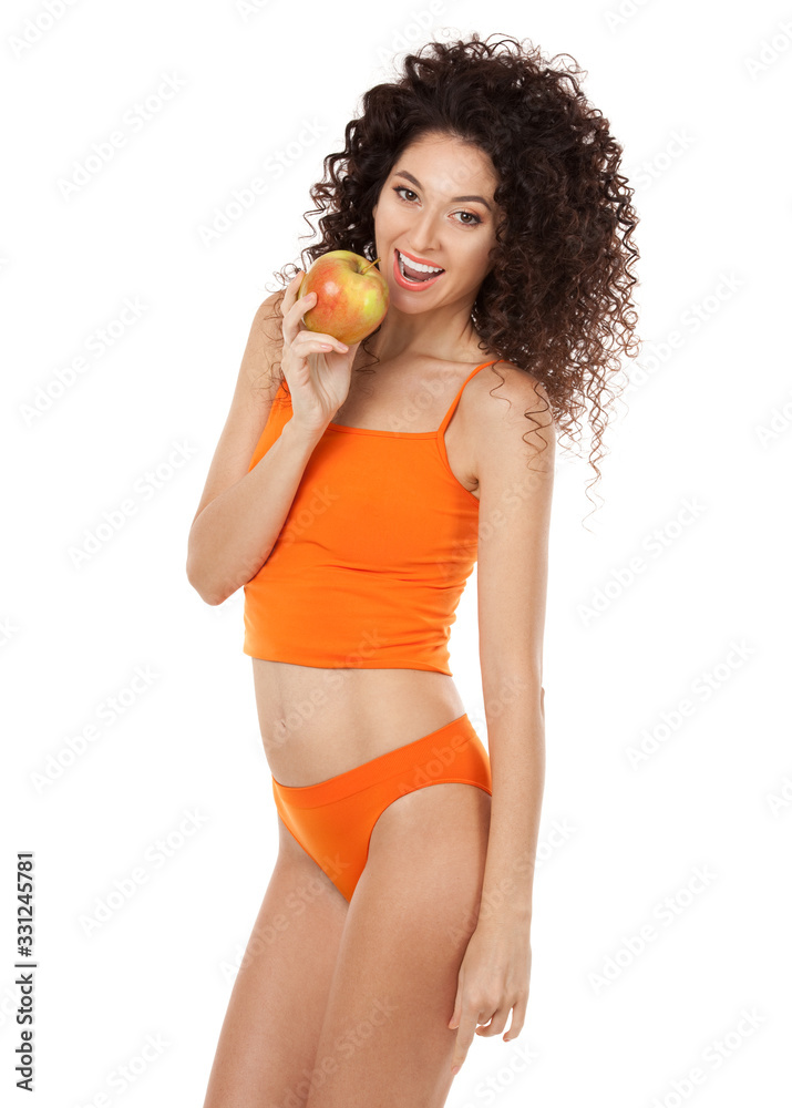 Cute curly woman with beautiful snow-white smile in orange lingerie holding big apple. Healthy lifestyle and nutrition, dieting, weight loss, cosmetology, dental care and healthy teeth conсept Cute curly woman with beautiful snow-white smile in orange lingerie holding big apple. Healthy lifestyle and nutrition, dieting, weight loss, cosmetology, dental care and healthy teeth conсept