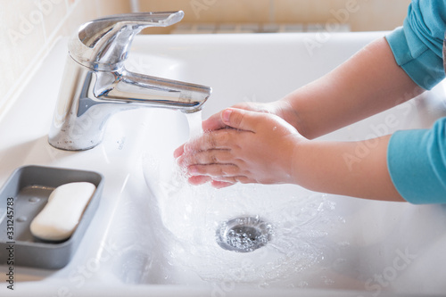Washing hands child rinsing soap with running water at sink, Coronavirus prevention hand hygiene. Covid-19 pandemic protection by cleaning arms