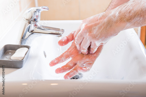 Washing hands man rinsing soap with running water at sink, Coronavirus prevention hand hygiene. Covid-19 pandemic protection by cleaning arms