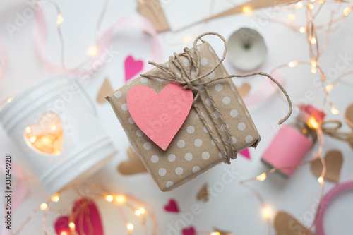 white background with modern gift wrapping. doted craft gift. present box with heart label tag with copy place and heartes for valentine's day on a white background with a garland photo