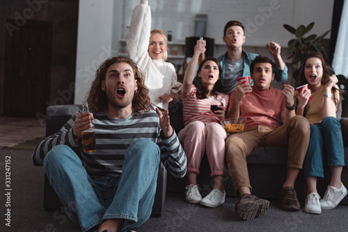 excited friends showing winner gesture while watching championship at home