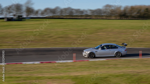 A panning shot of  a silver car cornering. © SnapstitchPhoto