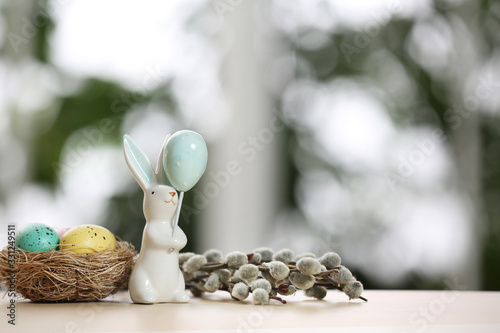 Festive composition with Easter eggs in decorative nest on table against blurred window. Space for text
