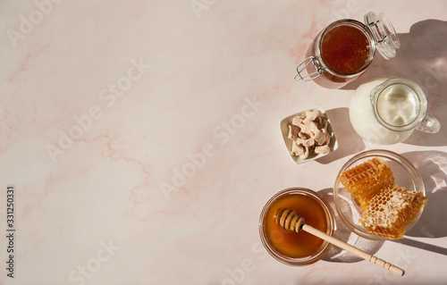 Natural home skin care. Ingredients for the mask. Sweet Golden honey, a jug of milk and natural live yeast on a pink marble background. The soft sunlight. Free space. Copy space.