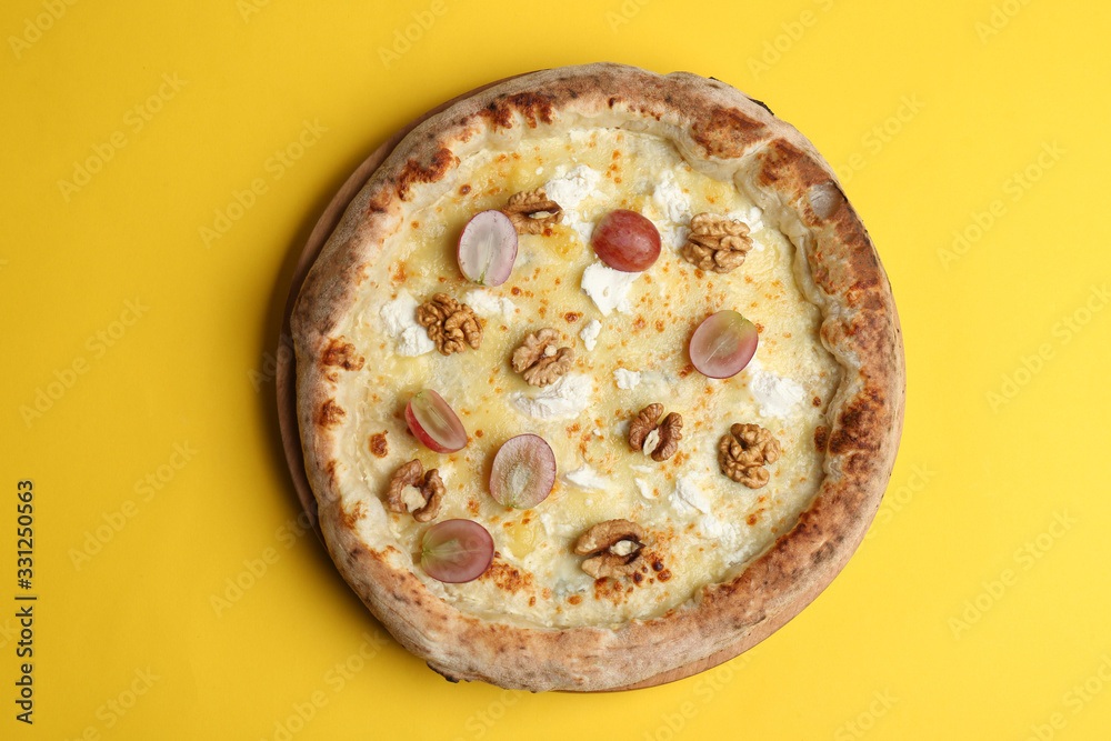 Delicious cheese pizza with grapes and walnuts on yellow background, top view Delicious cheese pizza with grapes and walnuts on yellow background, top view
