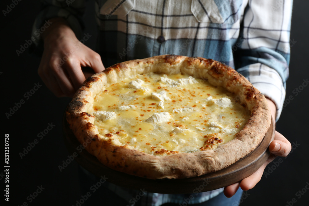 Woman holding delicious cheese pizza on black background, closeup