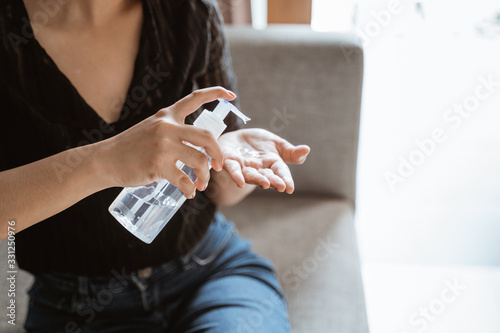 close up of woman using hand sanitizer gel at home to prevent virus, germ and bacteria