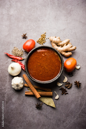 Fototapeta Naklejka Na Ścianę i Meble -  North Indian basic spicy Curry or masala for vegetables or chicken or mutton recipe shown with ingredients, served in a bowl. selective focus	homemade, restaurant, hot, oil, dark, red, indian, india, 