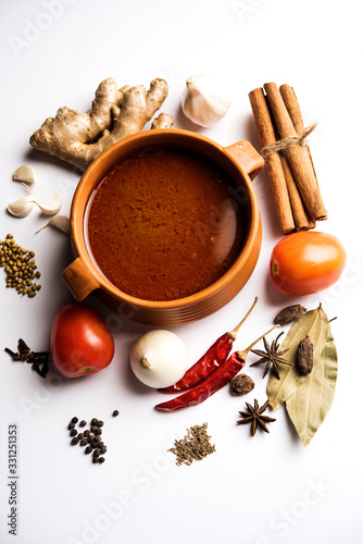 North Indian basic spicy Curry or masala for vegetables or chicken or mutton recipe shown with ingredients, served in a bowl. selective focus homemade, restaurant, hot, oil, dark, red, indian, india, 