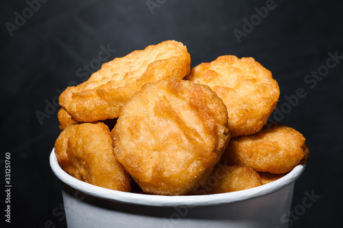 Bucket with delicious chicken nuggets on grey background, closeup