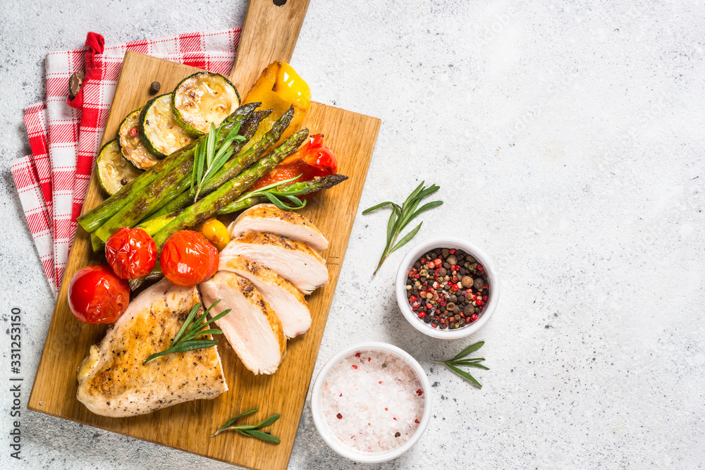 Chicken breast grilled with vegetables on a wooden serving board. Chicken breast grilled with vegetables on a wooden serving board.